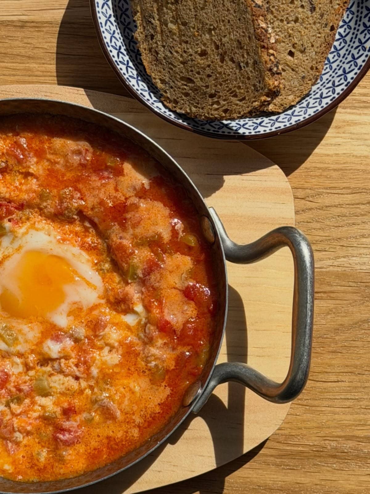 Menemen mit Ei in der Pfanne, dazu Brot